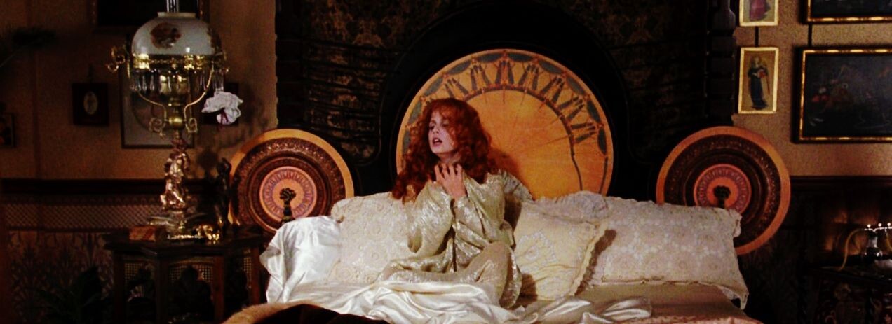 Still from movie: Lucy Westenra sitting up in bed clutching at her throat.