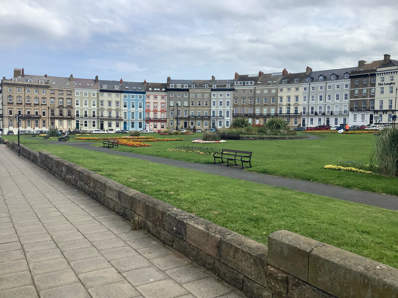 A crescent-shaped row of buildings behind a large green space.