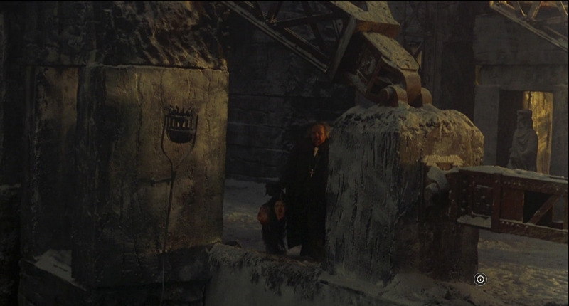 Still from movie /Bram Stoker’s Dracula/ (1992) showing Van Helsing walking amid the castle's massive stone structures with three heads dangling from his hand